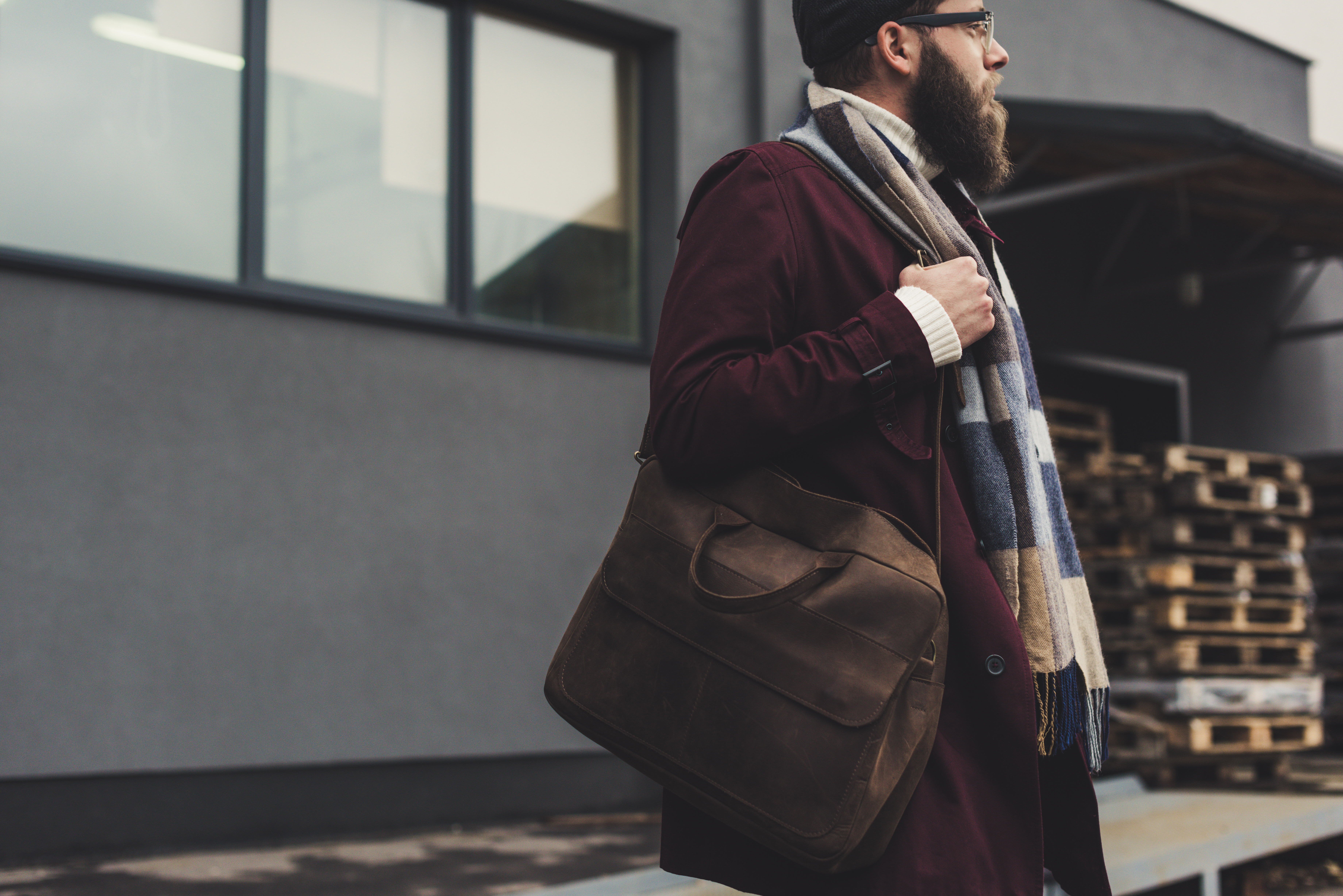 young bearded man in stylish clothing with leather bag